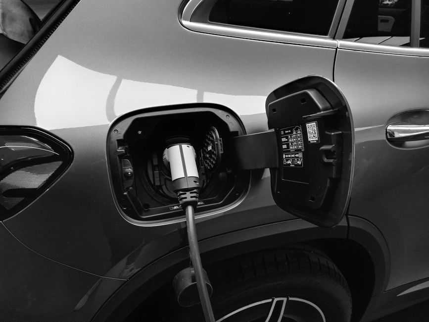 Black and white close-up of a charging cable plugged into an electric car's open charging port