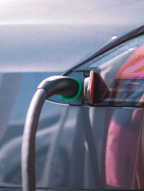 Close-up of a charging connector with a green light plugged into an electric car's port